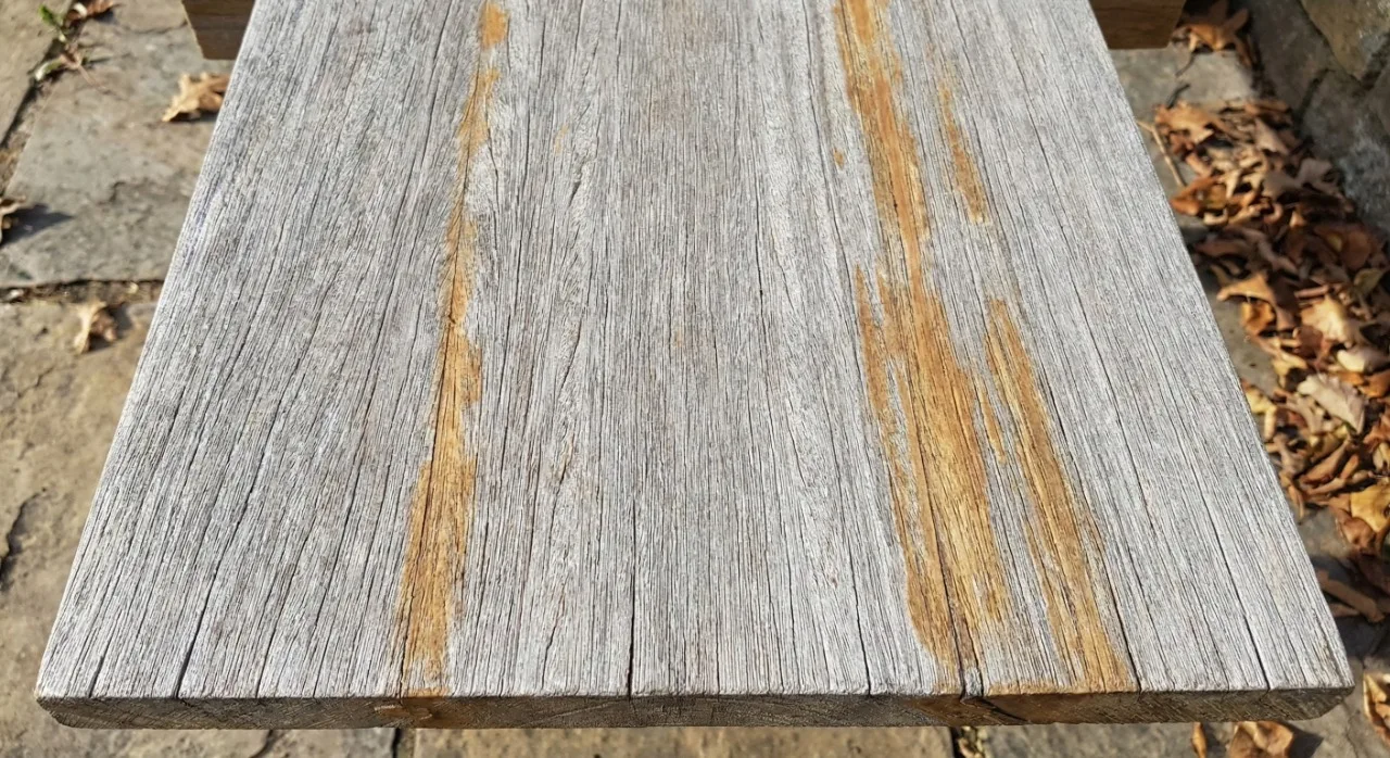 Teak wood after 9 months of outdoor weathering showing mostly grey surface with remaining golden-brown undertones